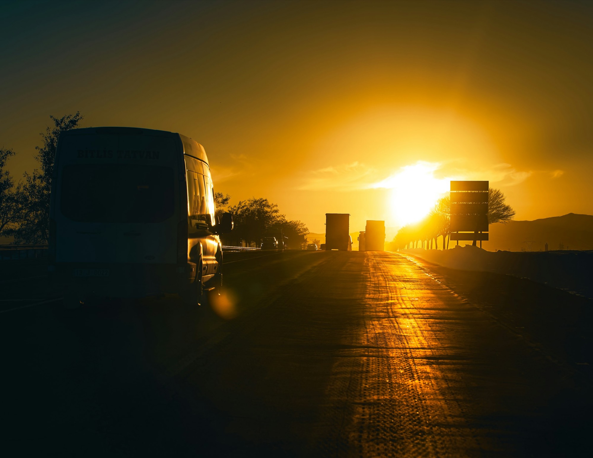 Caminhão rodando em rodovia contra o sol dourado do amanhecer