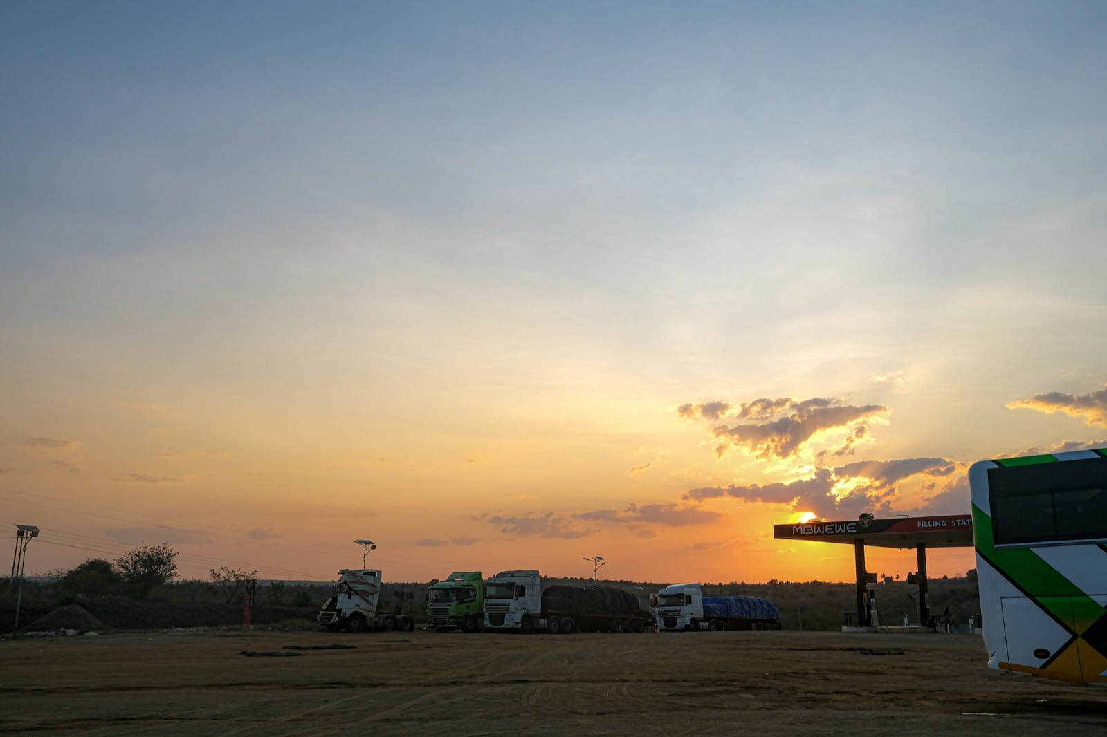 Pátio de posto com caminhões na silhueta do pôr do sol